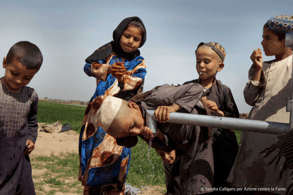 Bambini bevono da un rubinetto di acqua pulita appena intstallato, fondamentale per combattere fame e malnutrizione
